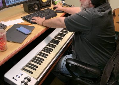 Image from a recording session inside a studio with a man manipulating a computer recording software