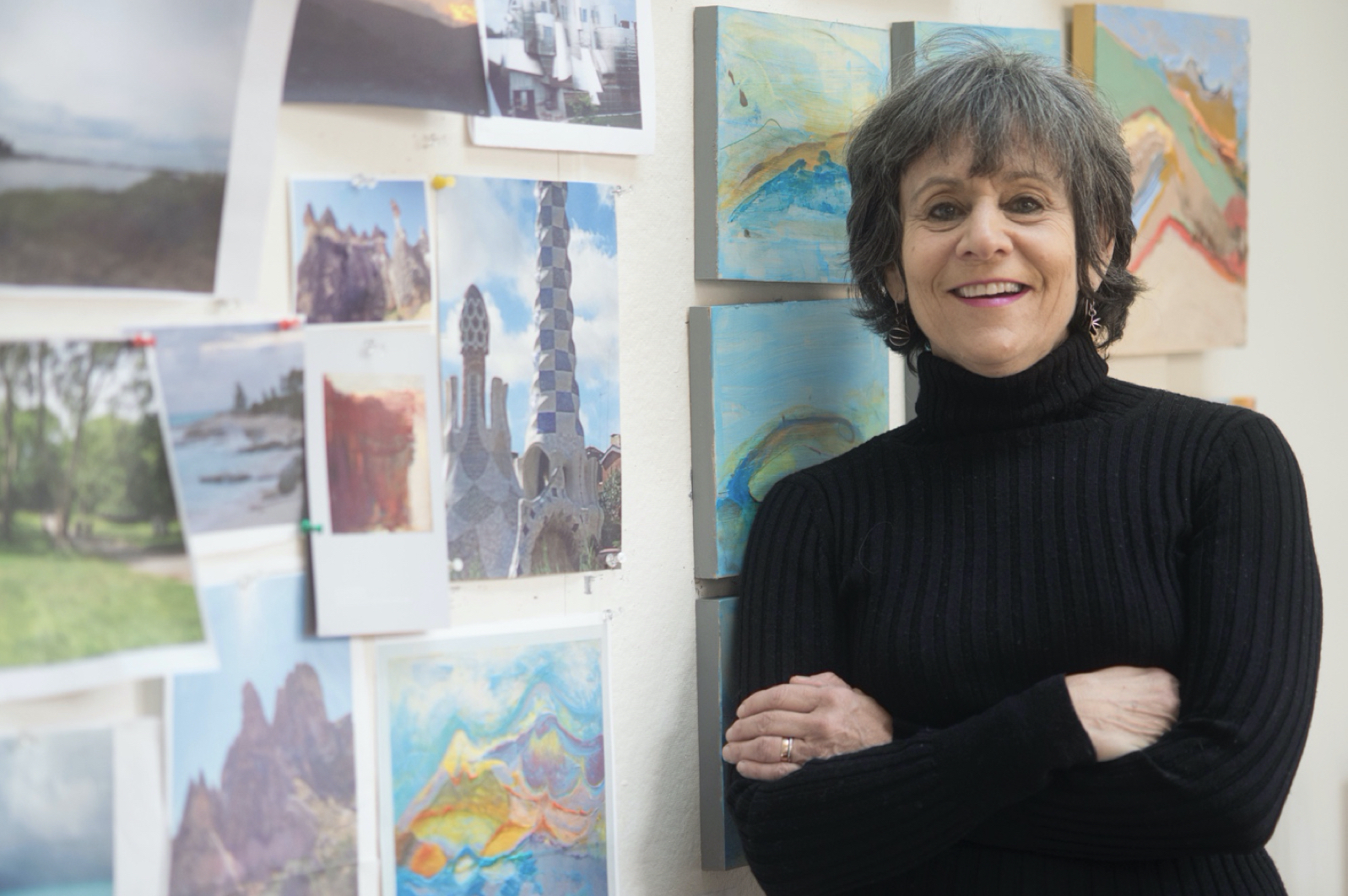 Beth Barry Headshot of Artist Beth Barry with Artwork on the wall to her left.
