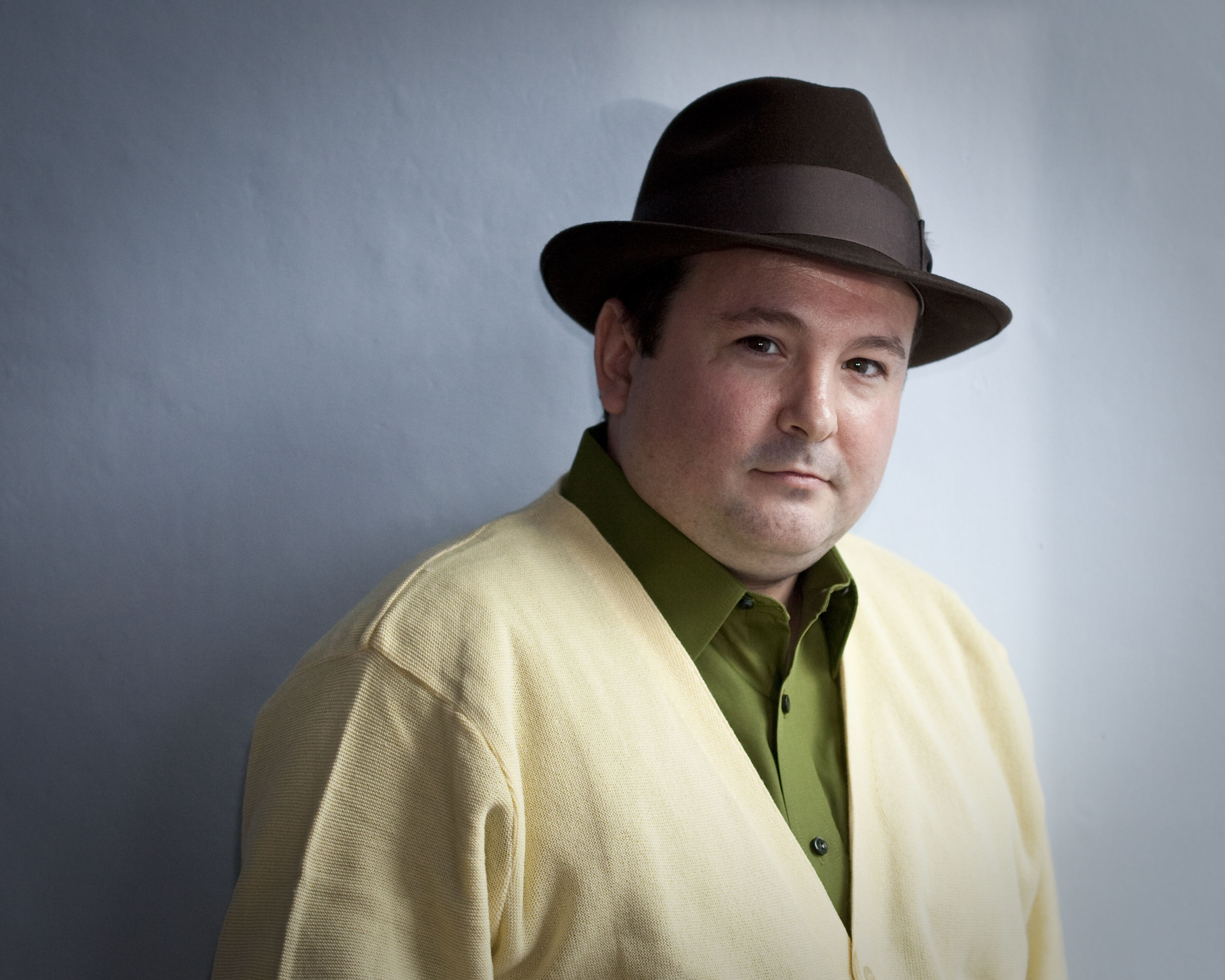 Full Color Headshot of Joshua Michael Stewart.Prose Poet from western Massachusetts.  Yellow Cashmere sweater, 1950's style, Olive Green shirt and brown stepped fedora hat.    