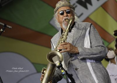 Saxophonist Charles Lloyd performing on tenor saxophone, colorful stage display behind him at the Newport Jazz Festival