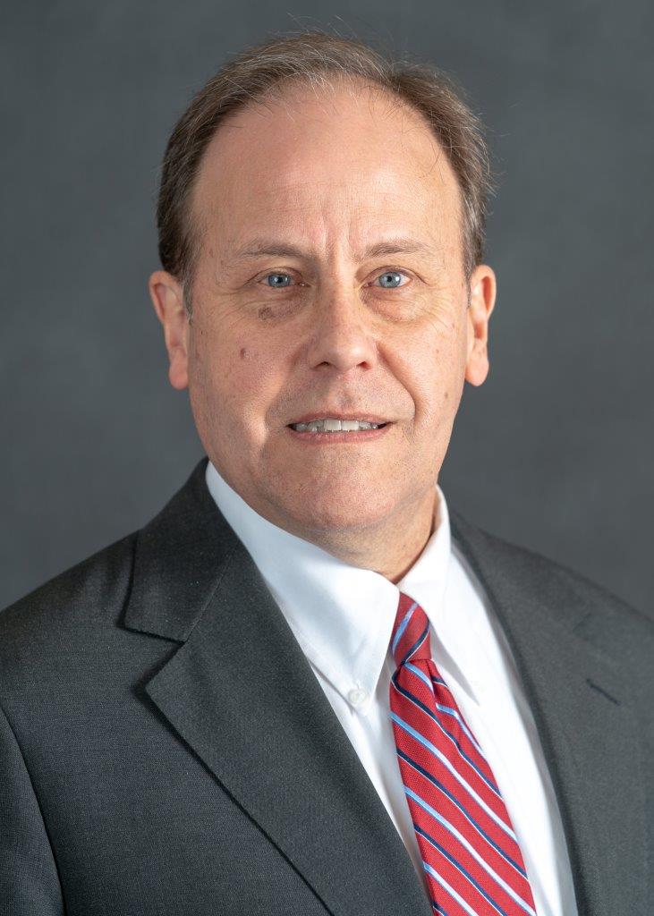 Full color headshot of our guest Thomas Greeley, Rotarian and financial expert working with Northwestern Financial.  Grey Suit, white shirt and red tie. 