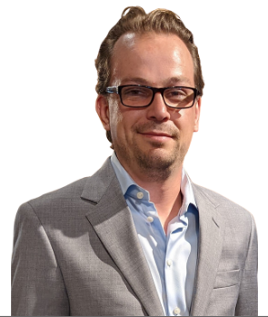 Full color headshot of Nattie Hussey, Economic Development Professional. Blue sport coat, arms folded with an industrial sheetmetal background