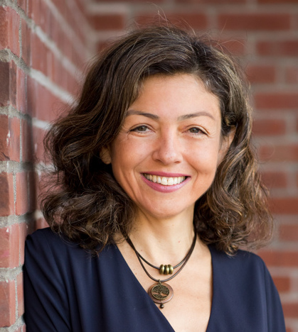 Full color headshot of Nattie Hussey, Economic Development Professional. Blue sport coat, arms folded with an industrial sheetmetal background